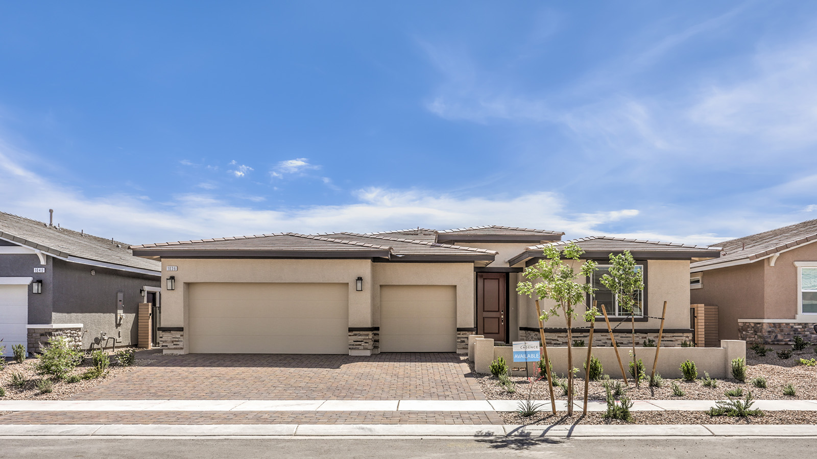 Our 2754 model home in the Heartland Manor community with tan and brown exterior paint schemes, a flat tile roof, front yard landscaping, paver walkways, and a three-car garage.