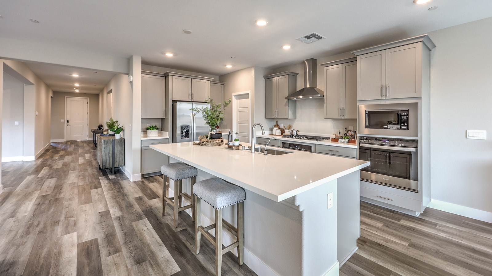 Our 2754 model kitchen in the Symmetry Manor Community with grey shaker style cabinets, granite countertops, a kitchen island, large pantry, and Whirlpool Stainless Steel appliances.