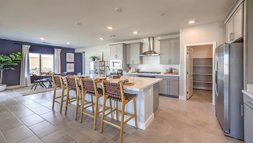 Our 2754 model kitchen in the Symmetry Manor Community with grey shaker style cabinets, granite countertops, a kitchen island, large pantry, and Whirlpool Stainless Steel appliances.