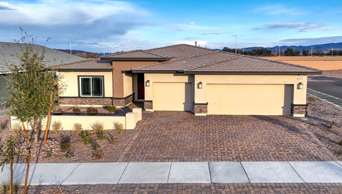 Our 2538 model home in the Heartland Manor community with tan and brown exterior paint schemes, a flat tile roof, front yard landscaping, paver walkways, and a three-car garage.