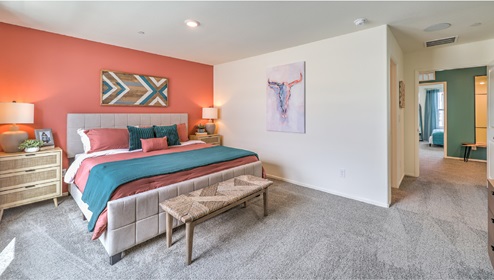 The Bedroom One Suite in our Tribute Trails 1309 model with carpet flooring, an accent wall, walk-in closet, and recessed ceiling lights.