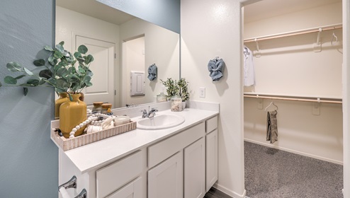 Attached to the Bedroom One Suite, our 1410 model bathroom with quartz/marble fusion countertops at the Bath Vanity, a walk-in closet, mirror, and white cabinets.