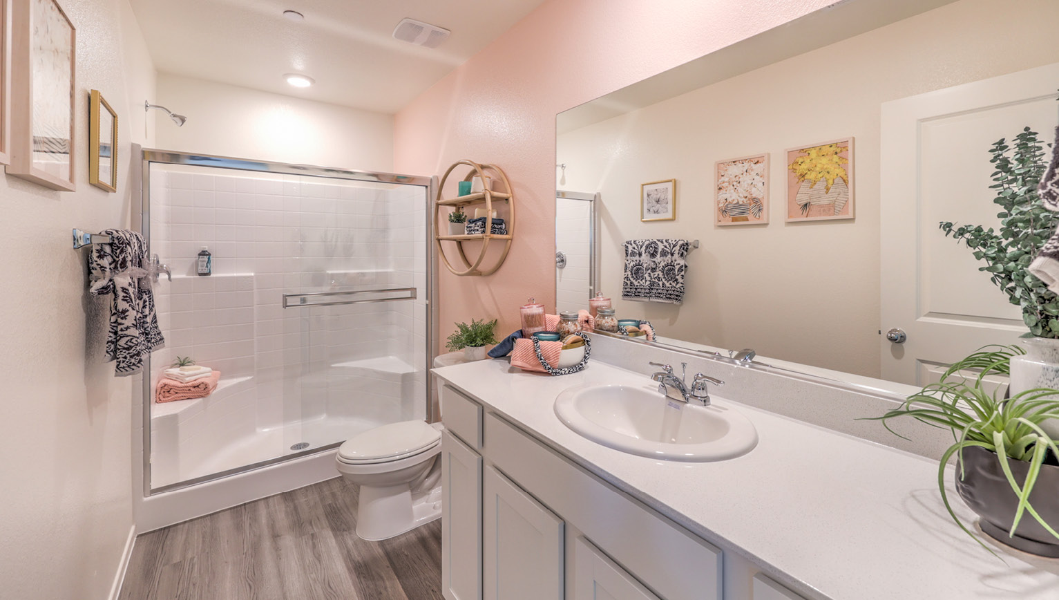Attached to the Bedroom One Suite, our 1309 model bathroom with quartz/marble fusion countertops at the Bath Vanity, a walk-in shower, mirror, and white cabinets.