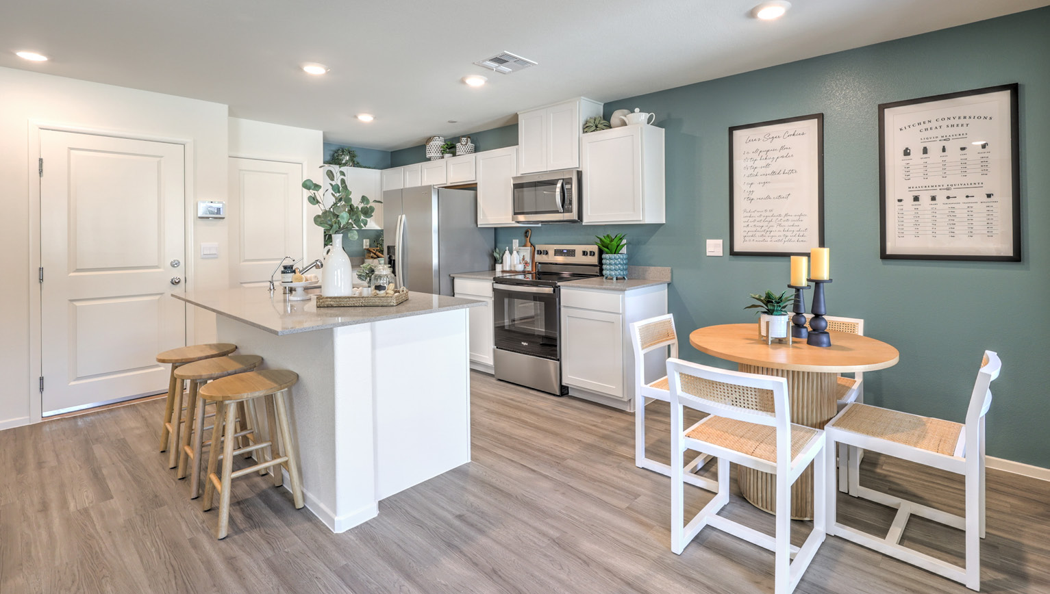 Our 1410 model kitchen in the Tempo Trails Community with white shaker style cabinets, quartz countertops, a kitchen island/seating area, and Whirlpool Stainless Steel appliances.