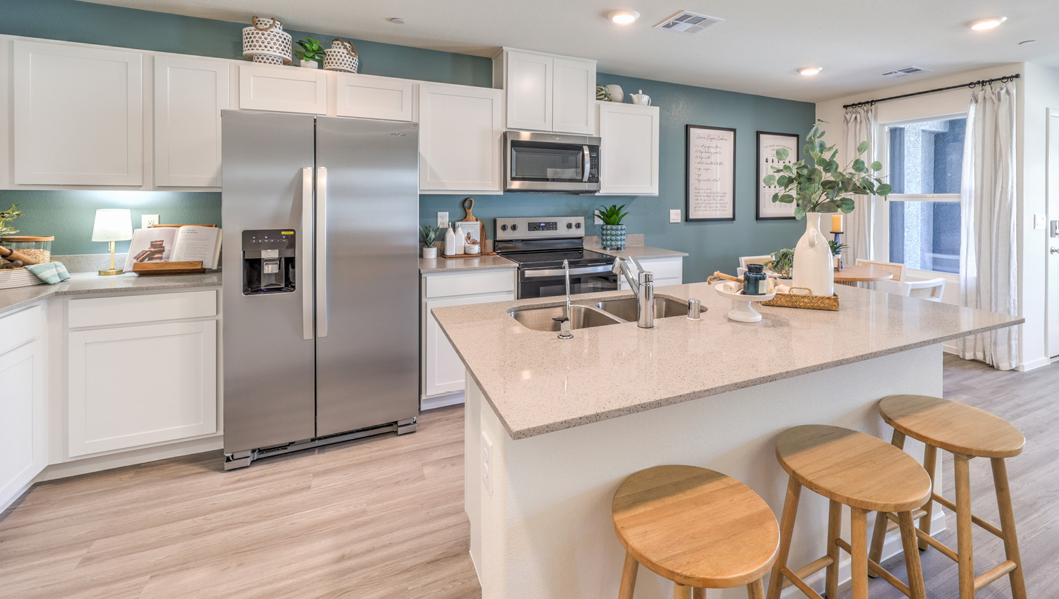 Our 1410 model kitchen in the Tempo Trails Community with white shaker style cabinets, quartz countertops, a kitchen island/seating area, and Whirlpool Stainless Steel appliances.