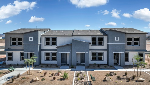 Our 1410 model home in the Tempo Trails community with navy and tan exterior paint schemes, common area landscaping, paved walkways, and a Flat Tile Roof.
