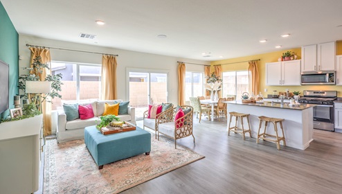 The Symmetry Bay 1865 Plan open concept Great Room with LVP panel flooring, two large windows, and a sliding door to the backyard.