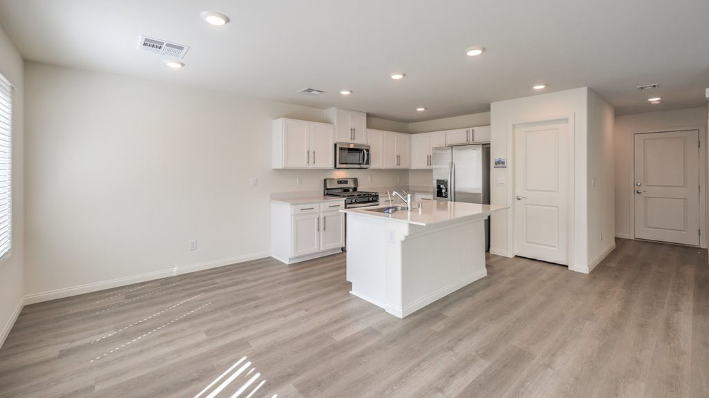 The Symmetry Bay 1715 Plan open concept Great Room with LVP panel flooring, large windows, and a sliding door to the backyard.