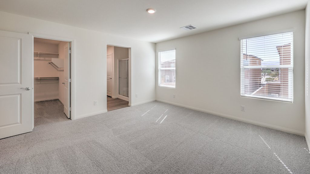The Bedroom One Suite in our Symmetry Bay 1715 model with carpet flooring, recessed ceiling lights, and a walk-in closet.