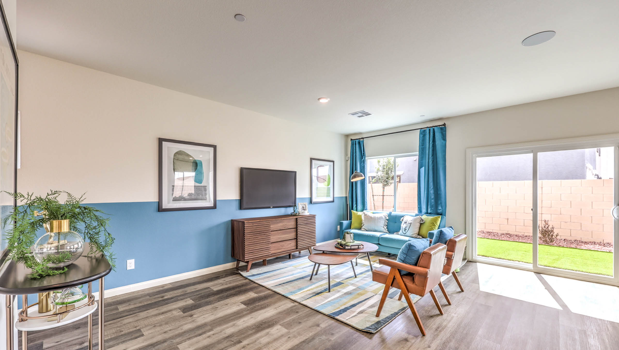 The Symmetry Bay 1802 Plan open concept Great Room with LVP panel flooring and a sliding door to the backyard.