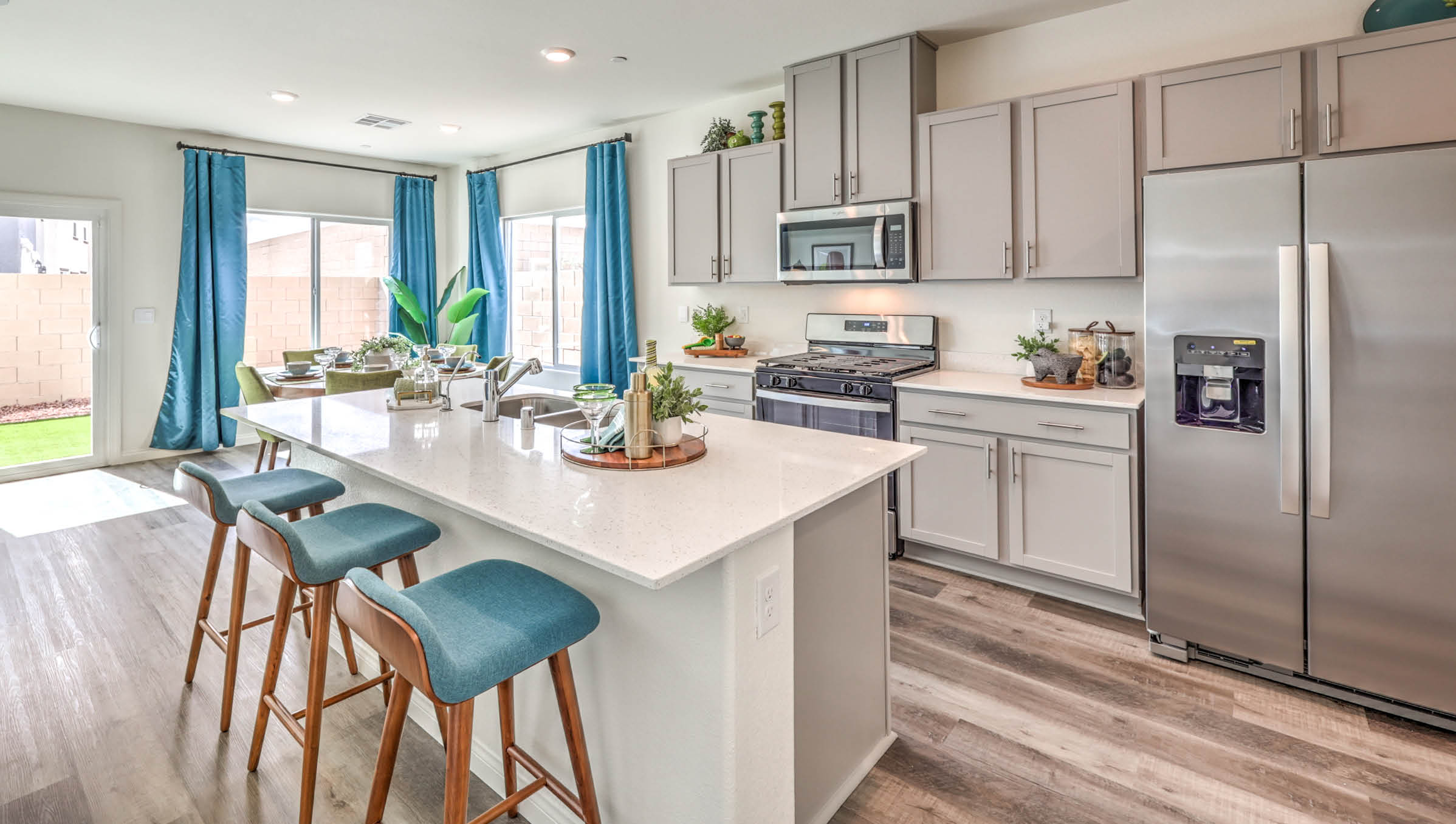 Our 1802 model kitchen in the Symmetry Bay Community with grey shaker style cabinets, Granite Slab countertops, a kitchen island, large pantry, and Whirlpool Stainless Steel appliances.