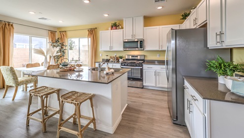 Our 1865 model kitchen in the Symmetry Bay Community with white shaker style cabinets, Granite Slab countertops, a kitchen island, and Whirlpool Stainless Steel appliances.