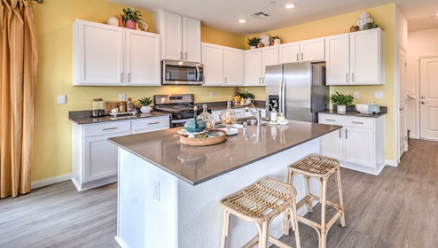 Our 1865 model kitchen in the Symmetry Bay Community with white shaker style cabinets, Granite Slab countertops, a kitchen island, and Whirlpool Stainless Steel appliances.