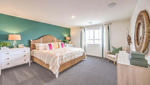 The Bedroom One Suite in our Symmetry Bay 1865 model with carpet flooring, walk-in closet, and a ceiling fan with a light kit.