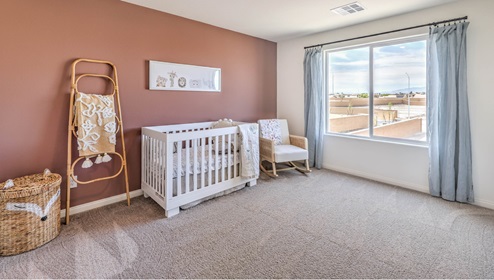 The Symmetry Falls 3000 Model Fourth Bedroom featuring plush wall-to-wall carpet, a large layout with soft natural light, and a walk-in closet. This versatile space is ideal for use as a nursery, guest room, or additional bedroom, offering comfort and privacy with easy access to nearby bathrooms.