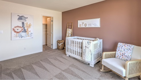 The Symmetry Falls 3000 Model Fourth Bedroom featuring plush wall-to-wall carpet, a large layout with soft natural light, and a walk-in closet. This versatile space is ideal for use as a nursery, guest room, or additional bedroom, offering comfort and privacy with easy access to nearby bathrooms.