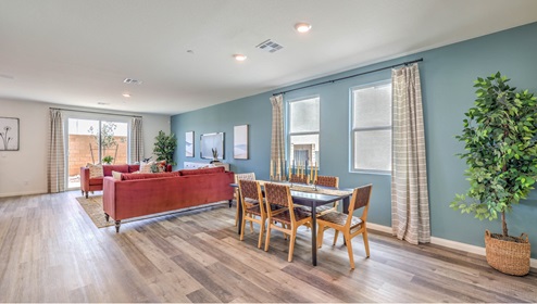 The Symmetry Falls 3000 Model open concept Dining Room and Great Room with Luxury Vinyl Plank flooring throughout, featuring expansive windows and a sliding glass door that provide natural light and access to the backyard. The space includes a designated dining area and a spacious living area, designed for seamless flow and functionality.