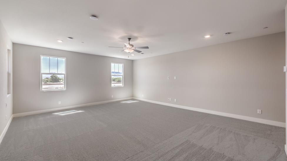 The Bedroom One Suite in our Symmetry Summit 3825 model with carpet flooring, large windows, and a ceiling fan with a light kit.