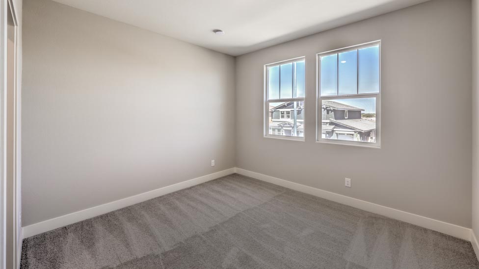 Bedroom Two in our Symmetry Summit 3825 model with carpet flooring, a walk-in closet, and two windows.