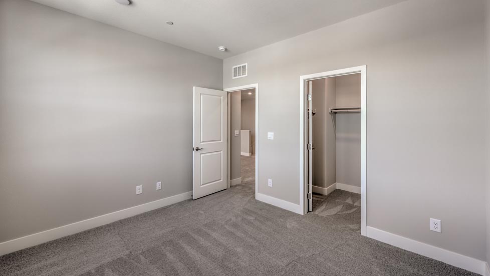 Bedroom Two in our Symmetry Summit 3825 model with carpet flooring, a walk-in closet, and two windows.