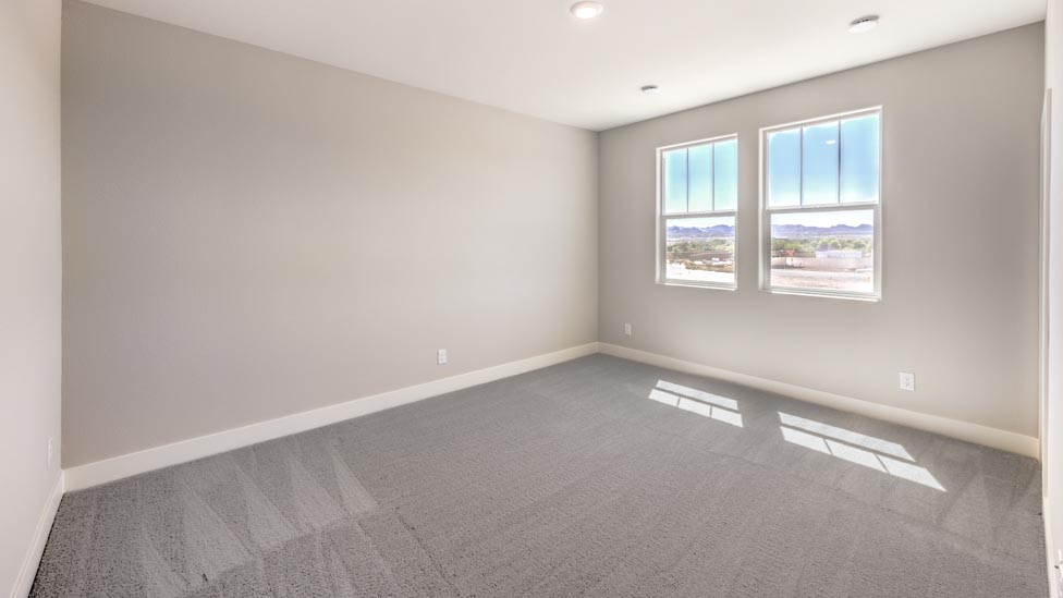 Bedroom Three in our Symmetry Summit 3825 model with carpet flooring, a walk-in closet, and two windows.