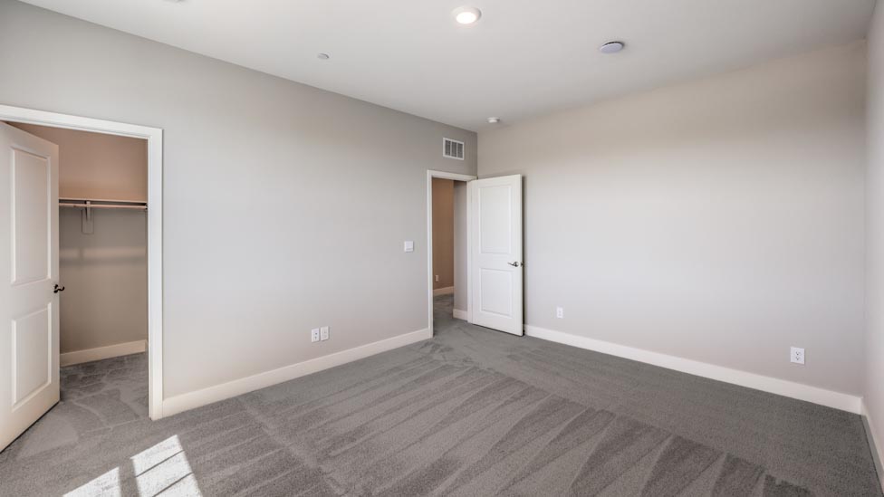 Bedroom Four in our Symmetry Summit 3825 model with carpet flooring, a walk-in closet, and two windows.