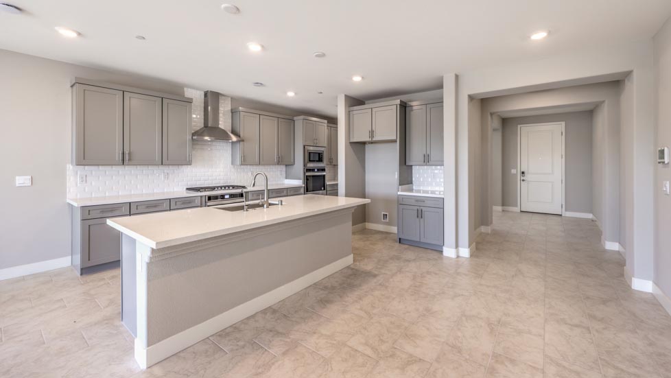 Our 3825 model kitchen in the Symmetry Summit Community with grey shaker style cabinets, quartz countertops, a kitchen island, 5-burner cooktop, large pantry, and Whirlpool Stainless Steel appliances.