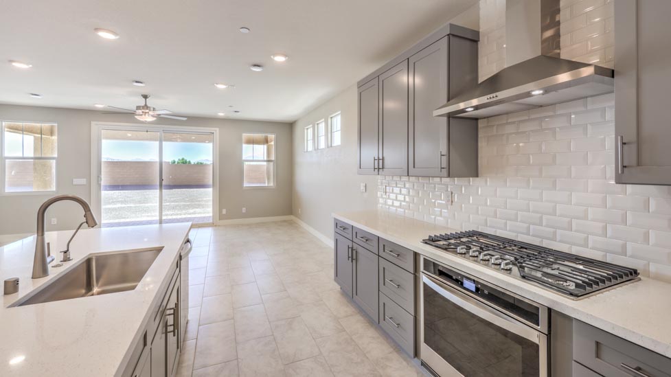 Our 3825 model kitchen in the Symmetry Summit Community with grey shaker style cabinets, quartz countertops, a kitchen island, 5-burner cooktop, large pantry, and Whirlpool Stainless Steel appliances.