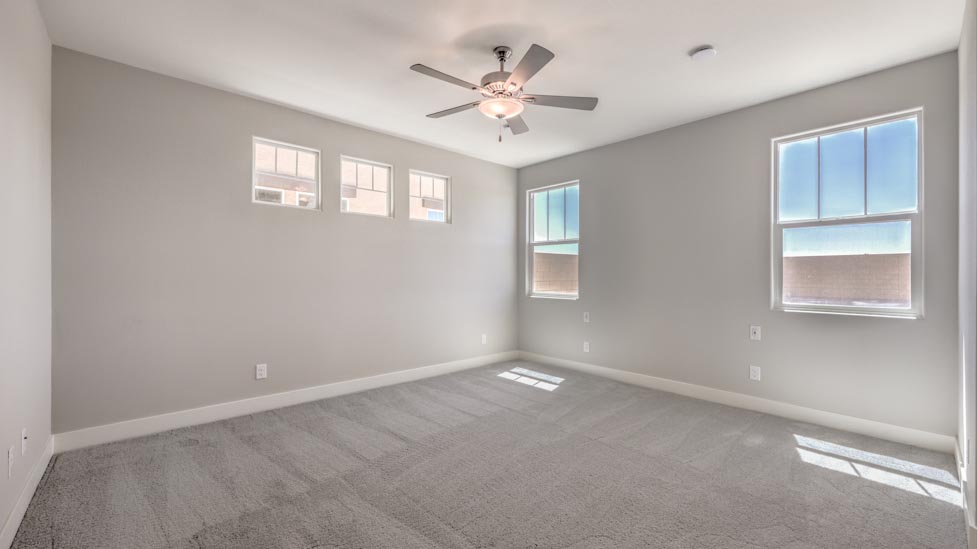 Bedroom Five in our Symmetry Summit 3825 model with carpet flooring, a walk-in closet, and windows.