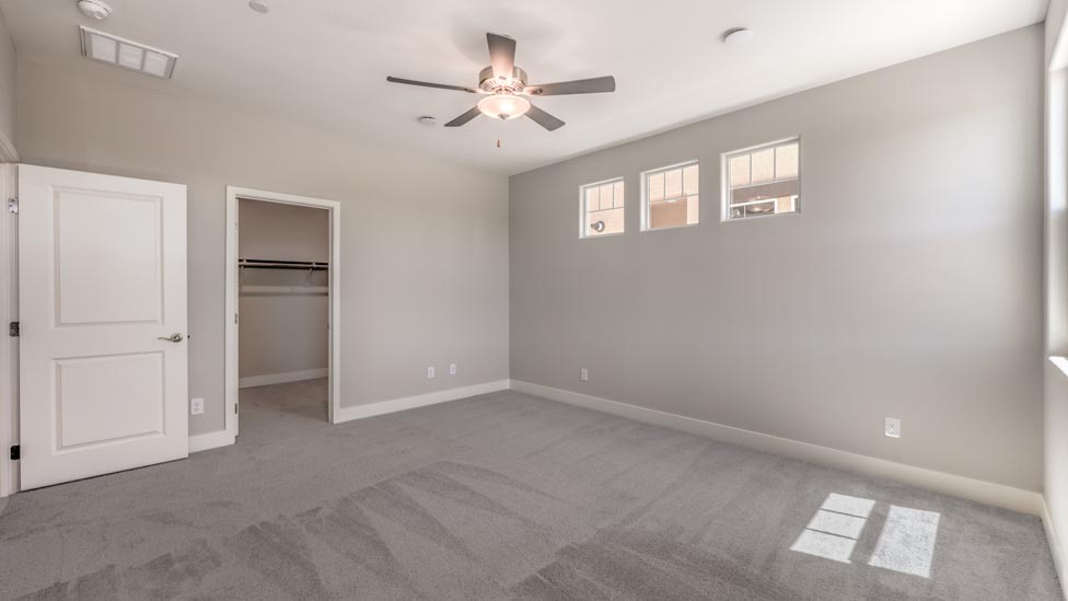 Bedroom Five in our Symmetry Summit 3825 model with carpet flooring, a walk-in closet, and windows.