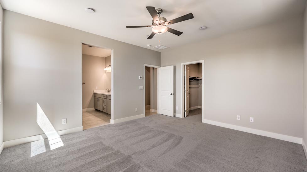 Bedroom Five in our Symmetry Summit 3825 model with carpet flooring, a walk-in closet, and windows.