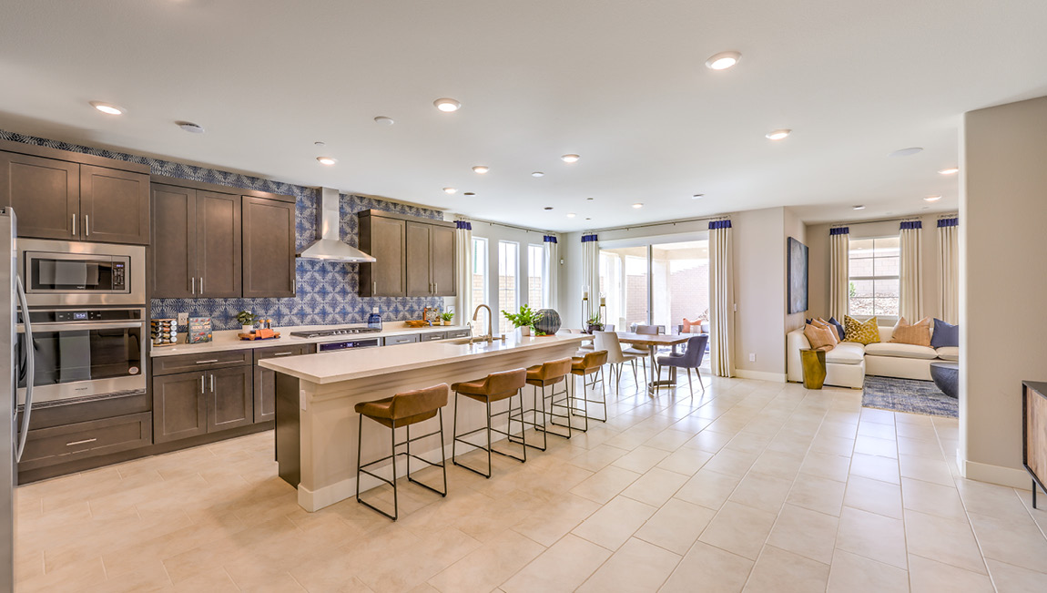 Our 4425 model kitchen in the Symmetry Summit Community with brown shaker style cabinets, quartz countertops, a kitchen island, 5-burner cooktop, large pantry, and Whirlpool Stainless Steel appliances.