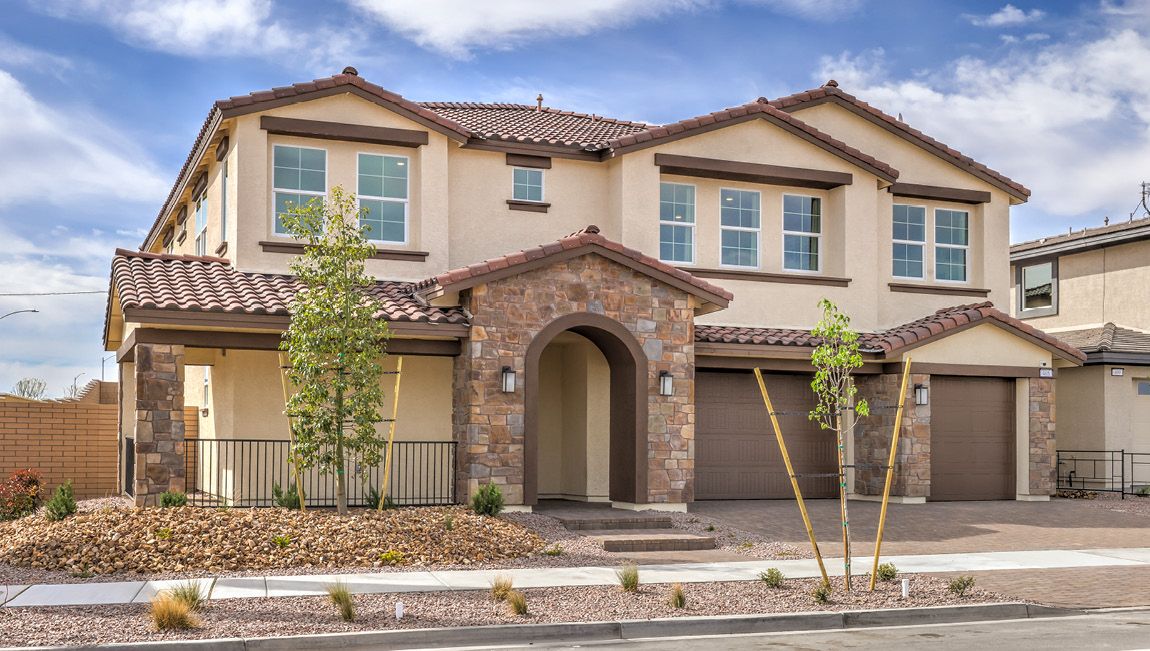 Our 4425 model home in the Symmetry Summit community with tan and brown exterior paint schemes, a flat tile roof, front yard landscaping, paver walkways, and a three-car garage.