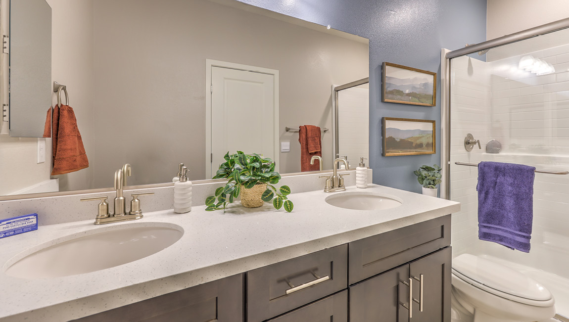 Bathroom Four in our Symmetry Summit 4425 Multigen Suite with granite countertops at the Bath Vanity, a walk-in shower, mirror, and brown cabinets.