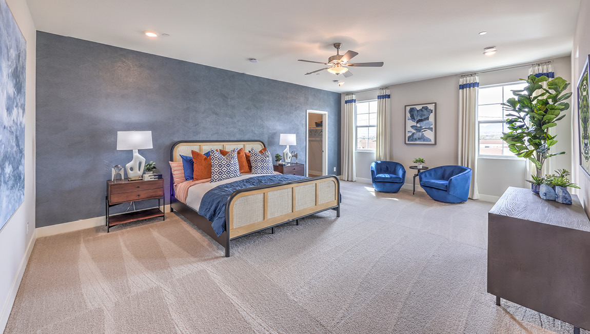 The Bedroom One Suite in our Symmetry Summit 4425 model with carpet flooring, large windows, and a ceiling fan with a light kit.