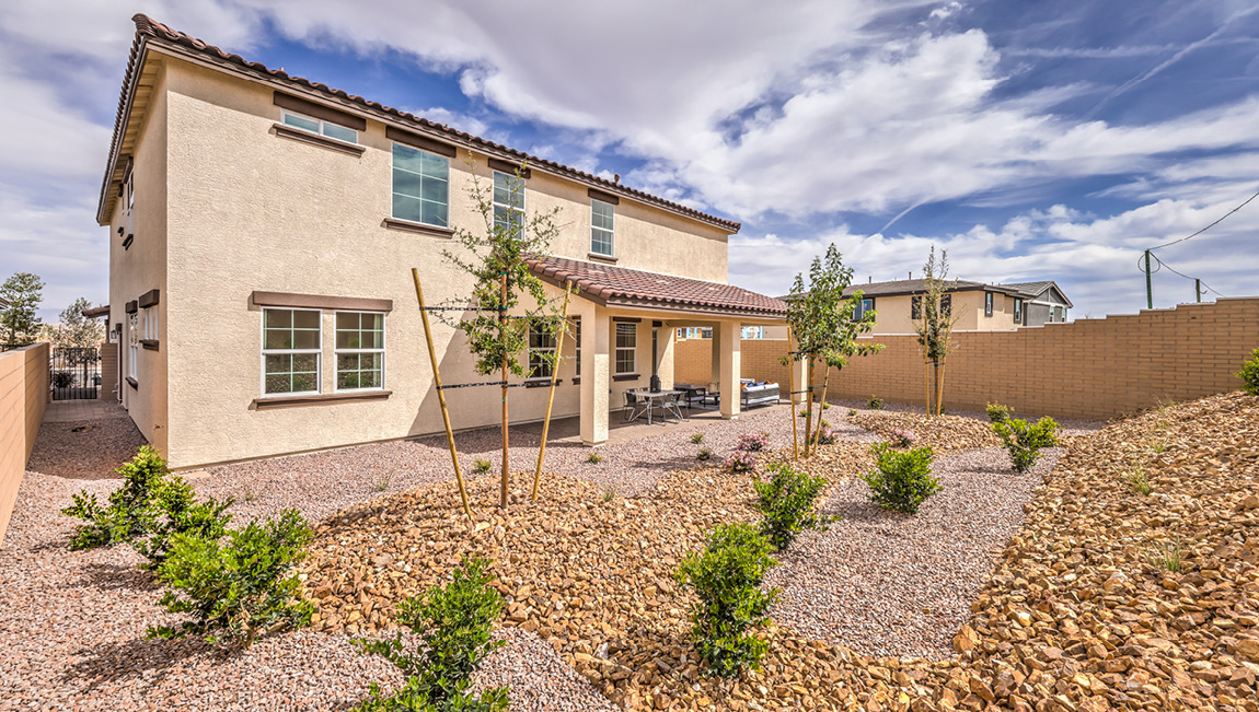 Our Symmetry Summit 4425 model backyard with landscaping and a large covered patio.