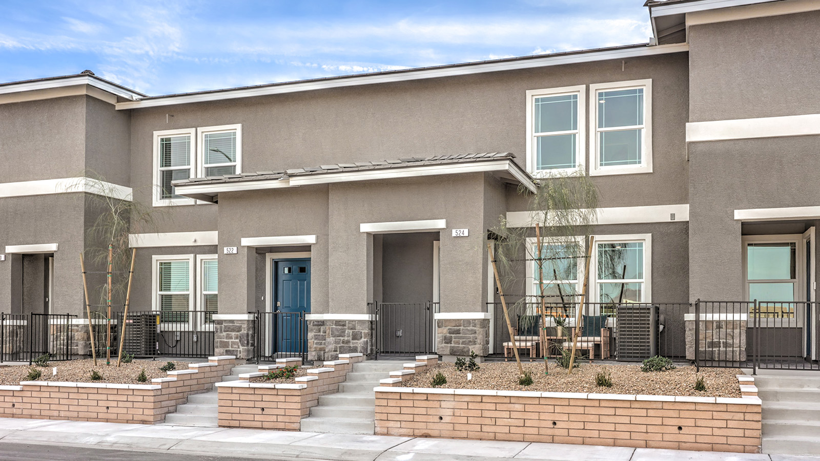 Our 1309 model home in the Symmetry Trails community with tan exterior paint schemes, common area landscaping, and paved walkways.