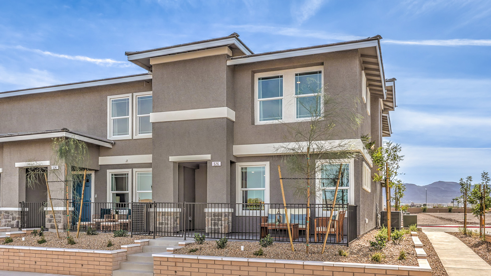 Our 1410 model home in the Symmetry Trails community with grey exterior paint schemes, common area landscaping, paved walkways, and a Flat Tile Roof.