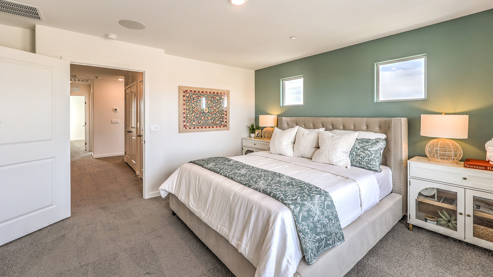The Bedroom One Suite in our Symmetry Trails 1410 model with carpet flooring, an accent wall, two windows.