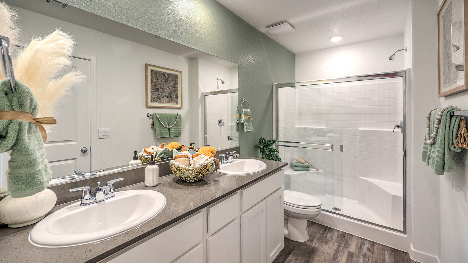 Attached to the Bedroom One Suite, our 1410 model bathroom with quartz/marble fusion countertops at the Bath Vanity, a walk-in closet, mirror, and white cabinets.