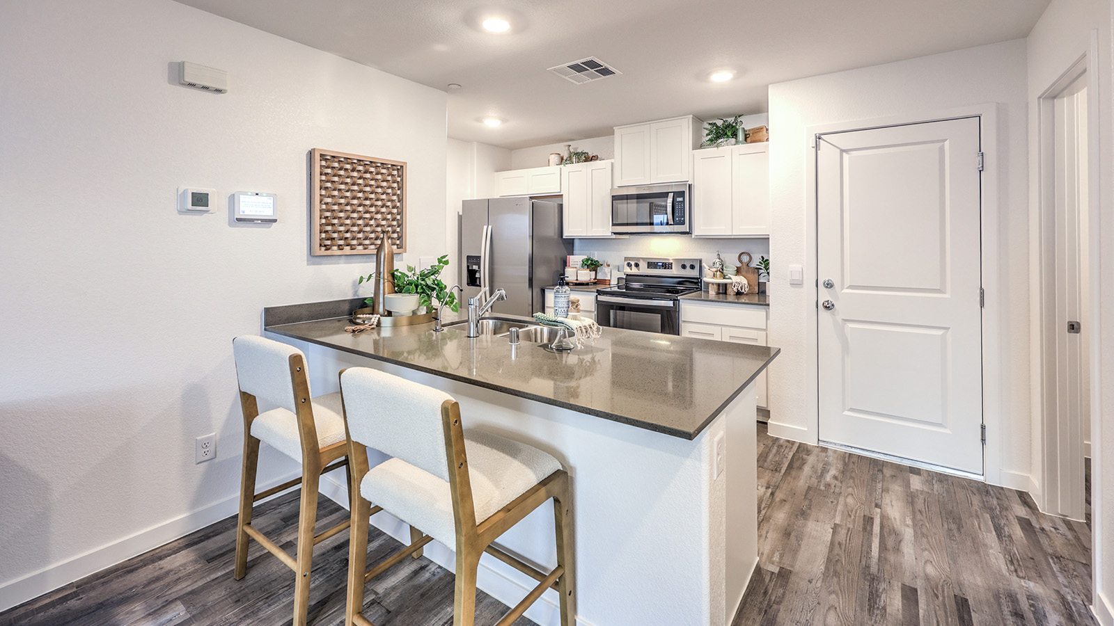 Our 1309 model kitchen in the Alpine Trails  Community with white shaker style style cabinets, quartz countertops, and Whirlpool Stainless Steel appliances.