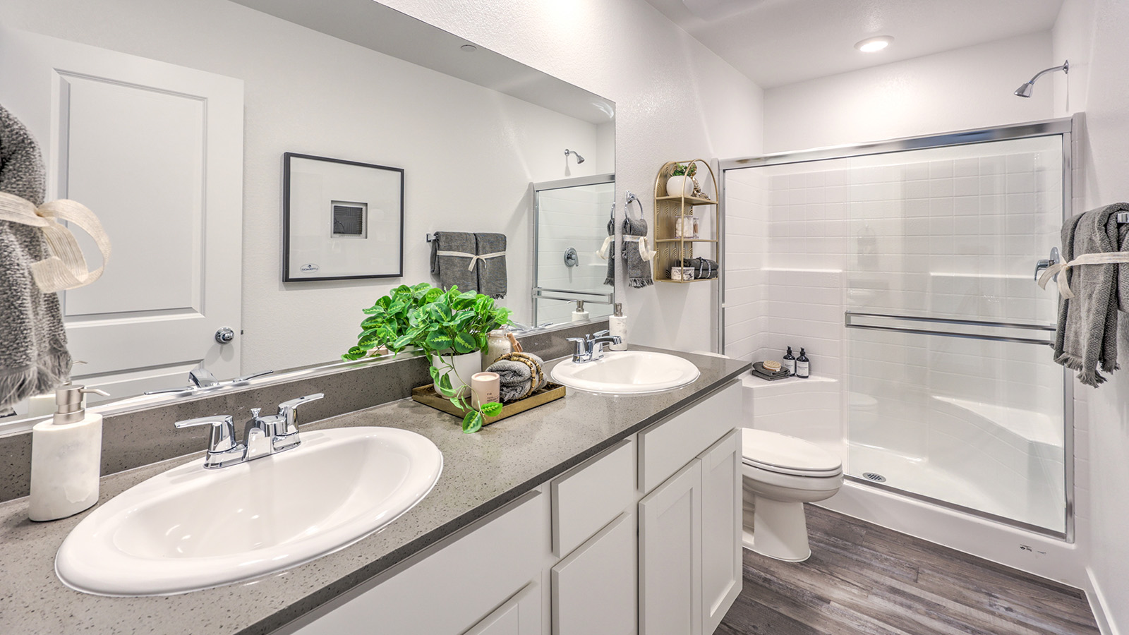 Attached to the Bedroom One Suite, our 1309 model bathroom with quartz/marble fusion countertops at the Bath Vanity, a walk-in shower, mirror, and white cabinets.