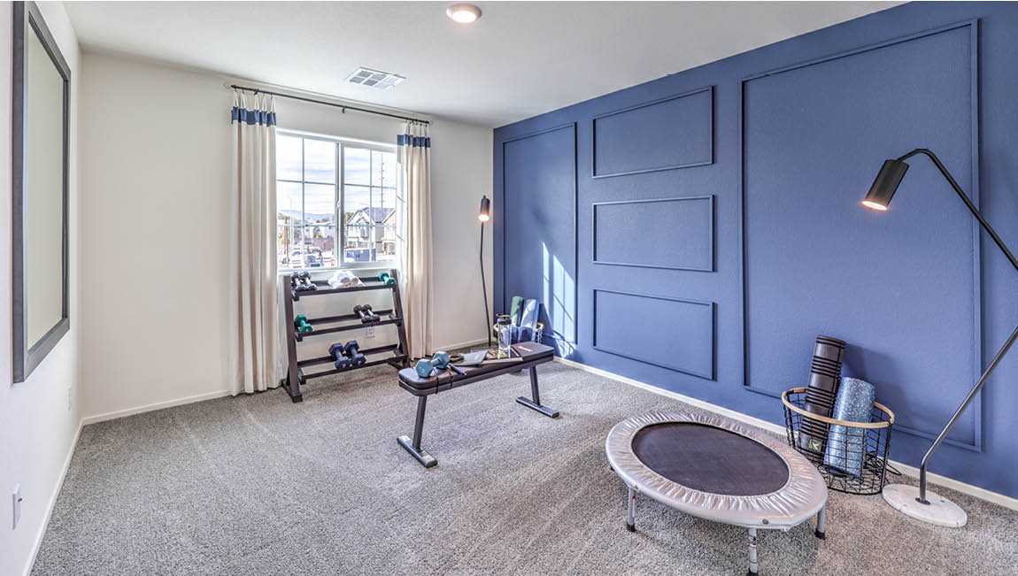 The Bedroom Two option in our Juno Pointe 1171 model with carpet flooring, furnished with gym equipment.