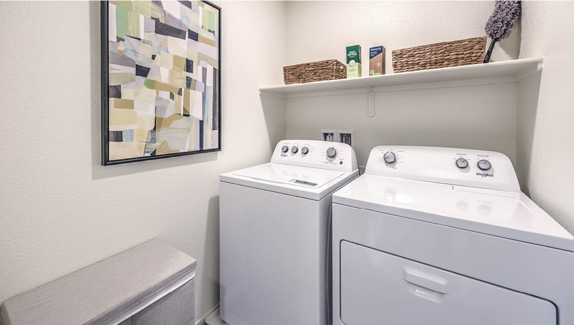 Our Juno Pointe 1171 model laundry room with a shelf and a washer and dryer.