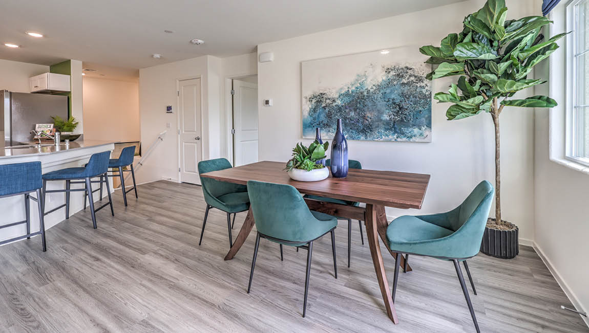 The Juno Pointe 1171 model Dining Room adjacent to the kitchen and great room with a table, large window, and door to the balcony.