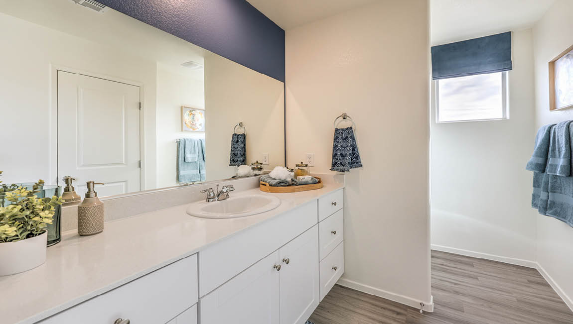Attached to the Bedroom One Suite, our 1349 model bathroom with quartz/marble fusion countertops at the Bath Vanity, a walk-in shower, mirror, and white cabinets.