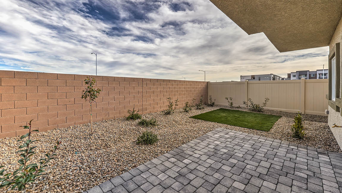 The backyard in our Juno Pointe 1349 plan with a covered patio, desert landscaping, and synthetic turf.