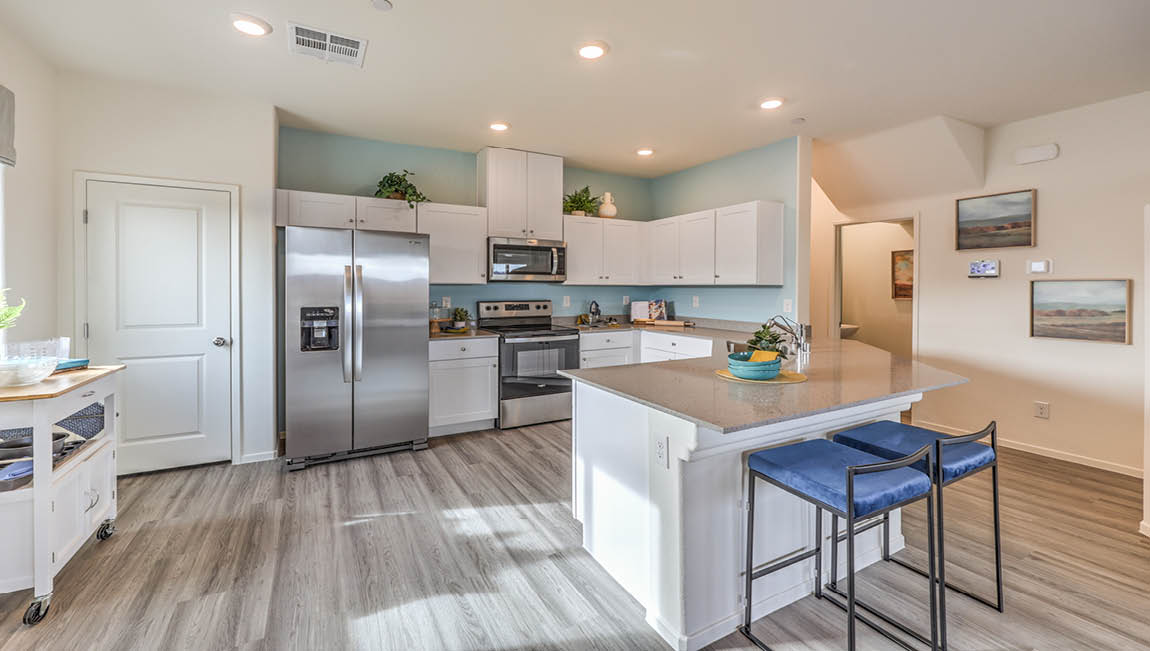 Our 1349 model kitchen in the Juno Pointe Community with white shaker style cabinets, quartz countertops, a Moen Pull Out Kitchen Faucet at the sink, and Whirlpool Stainless Steel appliances.