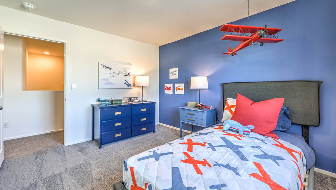 Bedroom Two in our Juno Pointe 1600 model with carpet flooring, a sliding closet, and a large window.