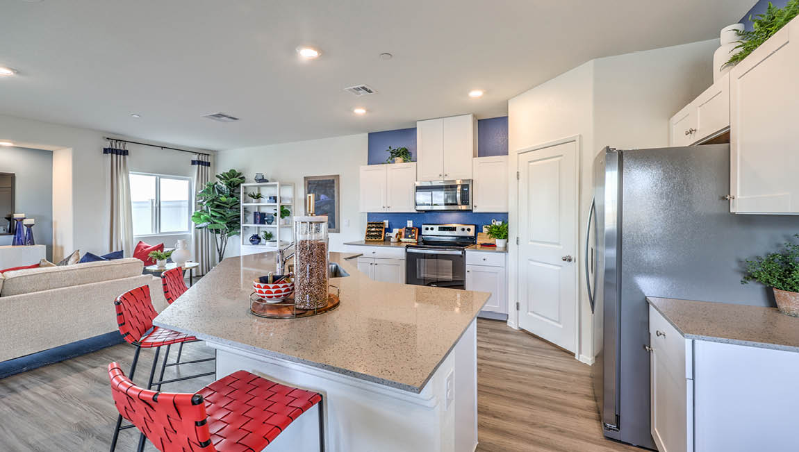 Our 1600 model kitchen in the Juno Pointe Community with white shaker style cabinets, quartz countertops, a Moen Pull Out Kitchen Faucet at the sink, and Whirlpool Stainless Steel appliances.